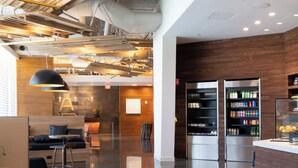A modern interior with a reception desk, seating area, and kitchen appliances. - The Ameswell Hotel (Mountain View)