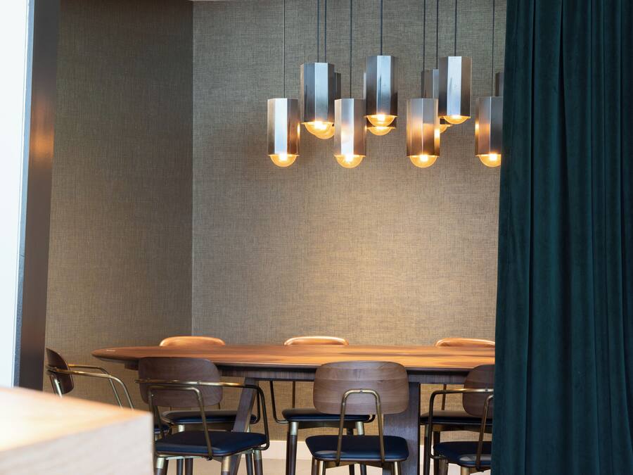 Un comedor moderno con una larga mesa de madera, varias sillas y una lámpara de techo original.