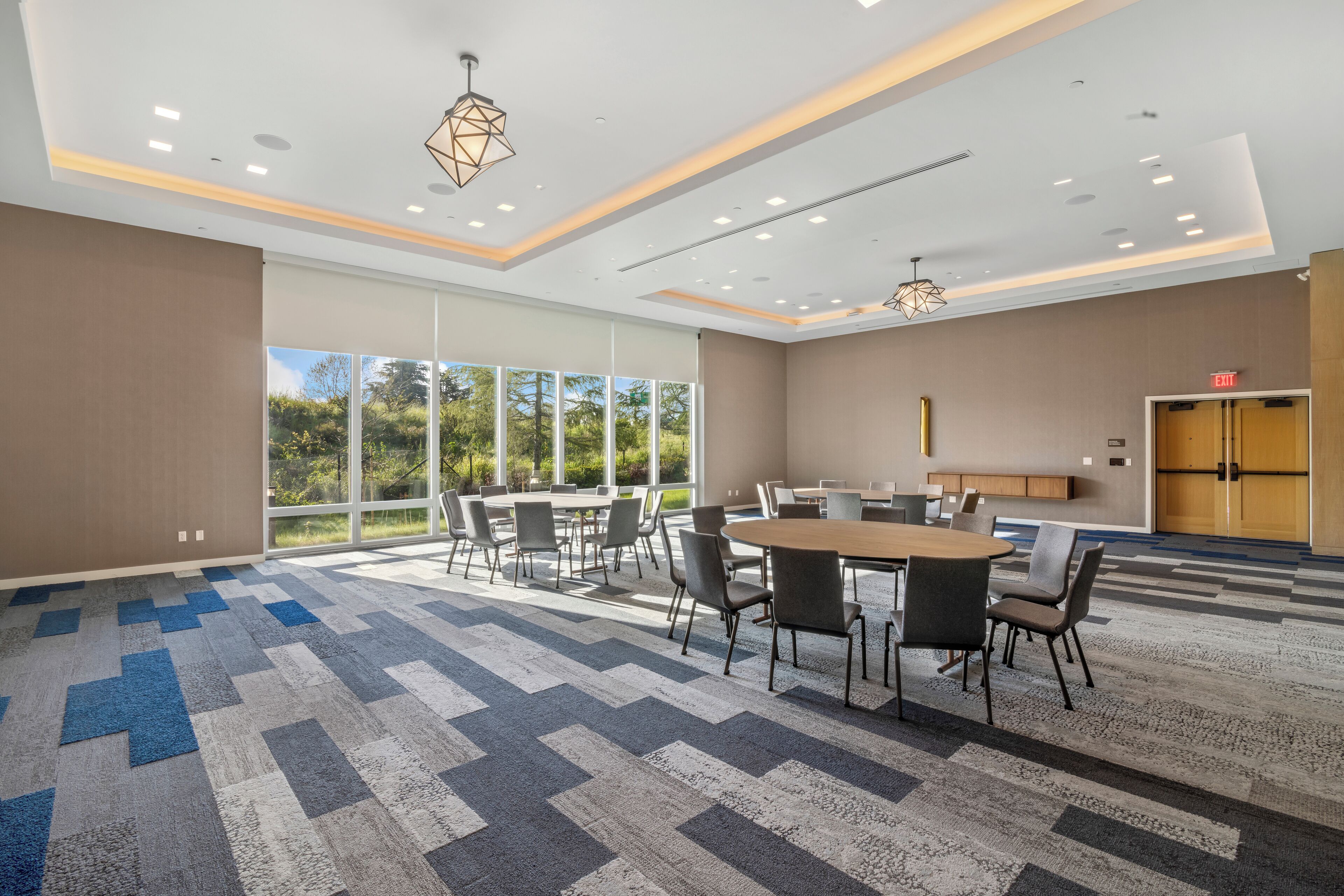 A modern conference room with a large table and chairs, large windows, and a carpeted floor.