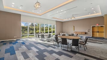 A modern conference room with a large table and chairs, large windows, and a carpeted floor.