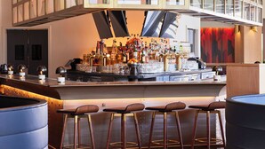 A modern bar area with a high ceiling, wooden beams, and a bar counter with stools. - The Ameswell Hotel (Mountain View)
