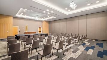 A conference room with rows of chairs, a long table, and a stage.