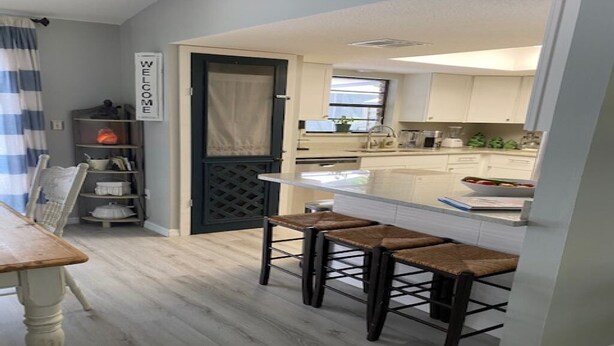 Una cocina moderna con barra, suelo de madera clara y un cartel que dice 'Welcome'.
