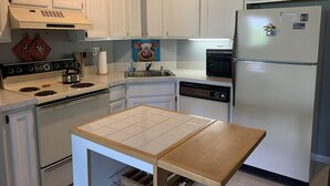 A kitchen with white cabinets, a stove, a sink, a refrigerator, and a small wooden table. - Redecorated! Great Location at Mount Snow, Free Shuttle, Pool/Hot Tub (West Dover)