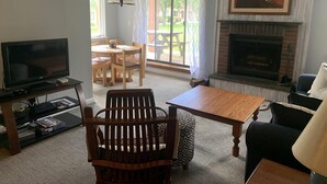 A living room with a fireplace, a television, a dining table with chairs, and a sofa. - Redecorated! Great Location at Mount Snow, Free Shuttle, Pool/Hot Tub (West Dover)
