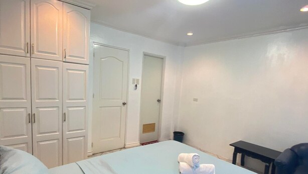Een slaapkamer met een bed, bureau, stoel en kast.