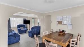 A living room with a sofa set, a dining table with chairs, and a TV. - Fishos Hangout 1 - Unit 1 Sinclair St 21 (BERMAGUI)
