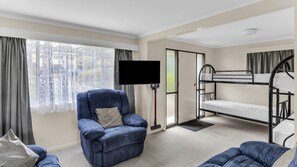 A room with a blue armchair, a bunk bed, a television, and a window with curtains. - Fishos Hangout 2 - Unit 2 Sinclair St 21 (BERMAGUI)