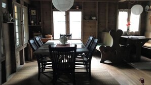 Comedor con mesa y sillas de madera, lámpara colgante y vista al exterior a través de una ventana.