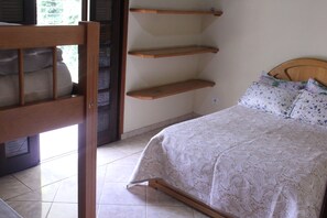 Um quarto com uma cama, cabeceira de madeira e um conjunto de prateleiras de madeira na parede.