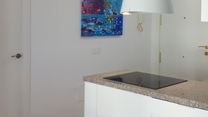 Una cocina moderna con armarios blancos, encimera de granito y una lámpara colgante.