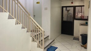 Un escalier menant à une porte portant l’inscription « Toilettes », avec un sol carrelé et une poubelle placée près de la porte.