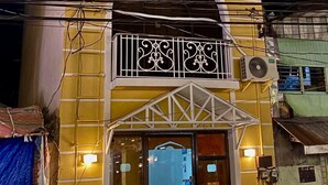 Un bâtiment à deux étages, doté d’un balcon à l’étage supérieur, d’une grande entrée en arc de cercle et d’un appareil de climatisation visible.