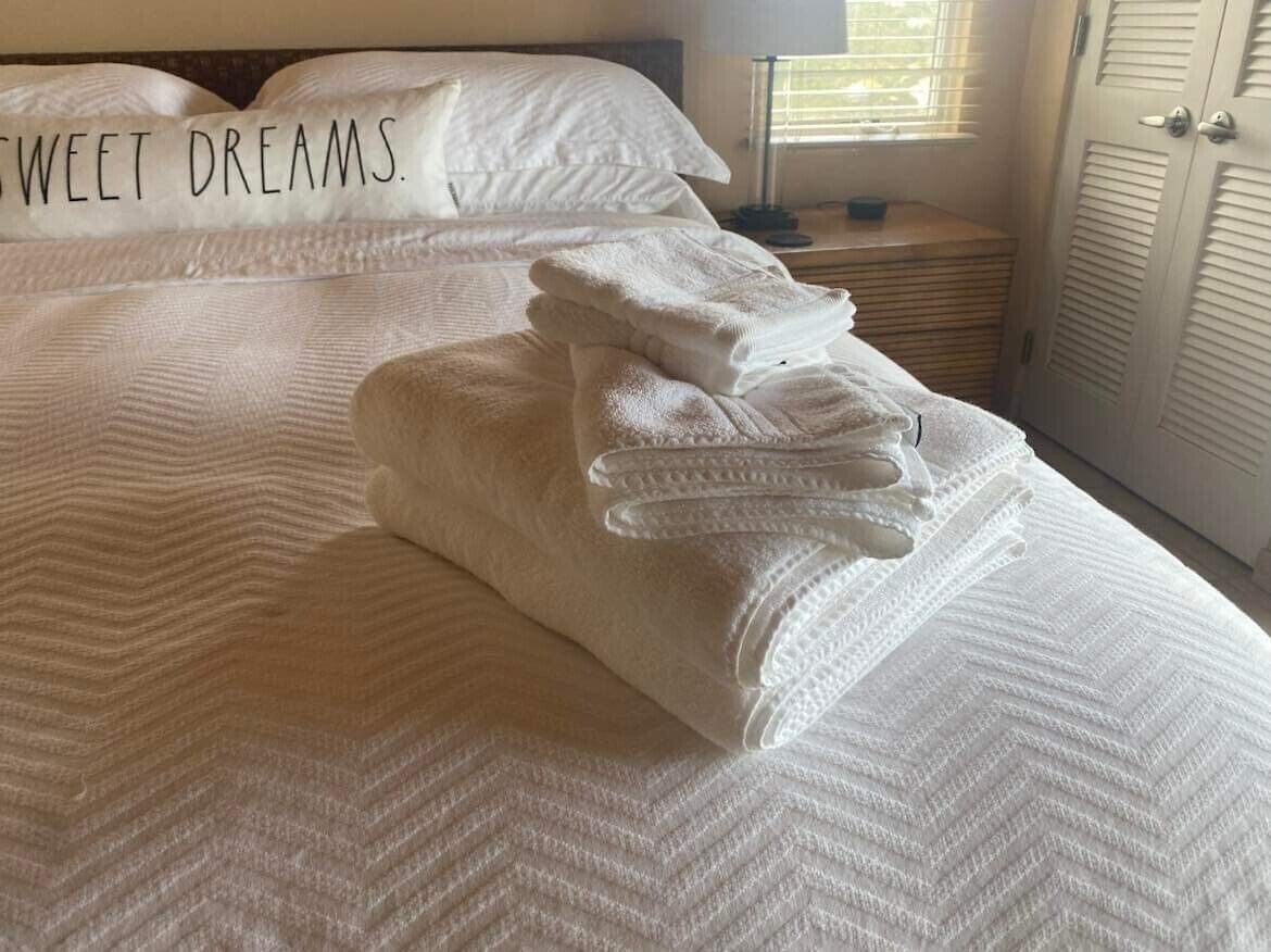 Un lit bien fait, avec des serviettes pliées et un oreiller orné de la mention « Doux rêves ».