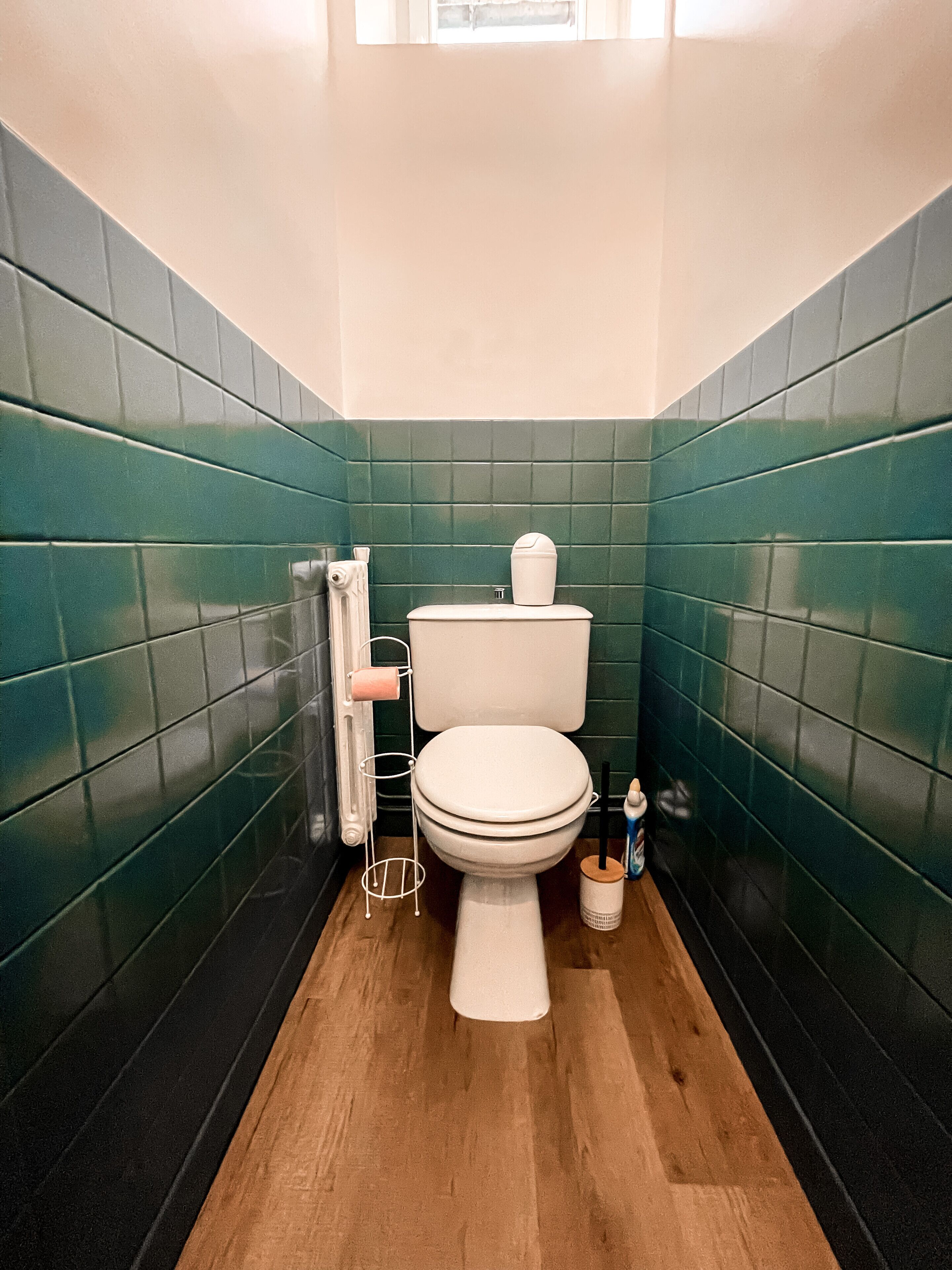Un baño con inodoro, porta papel higiénico y secador de manos.