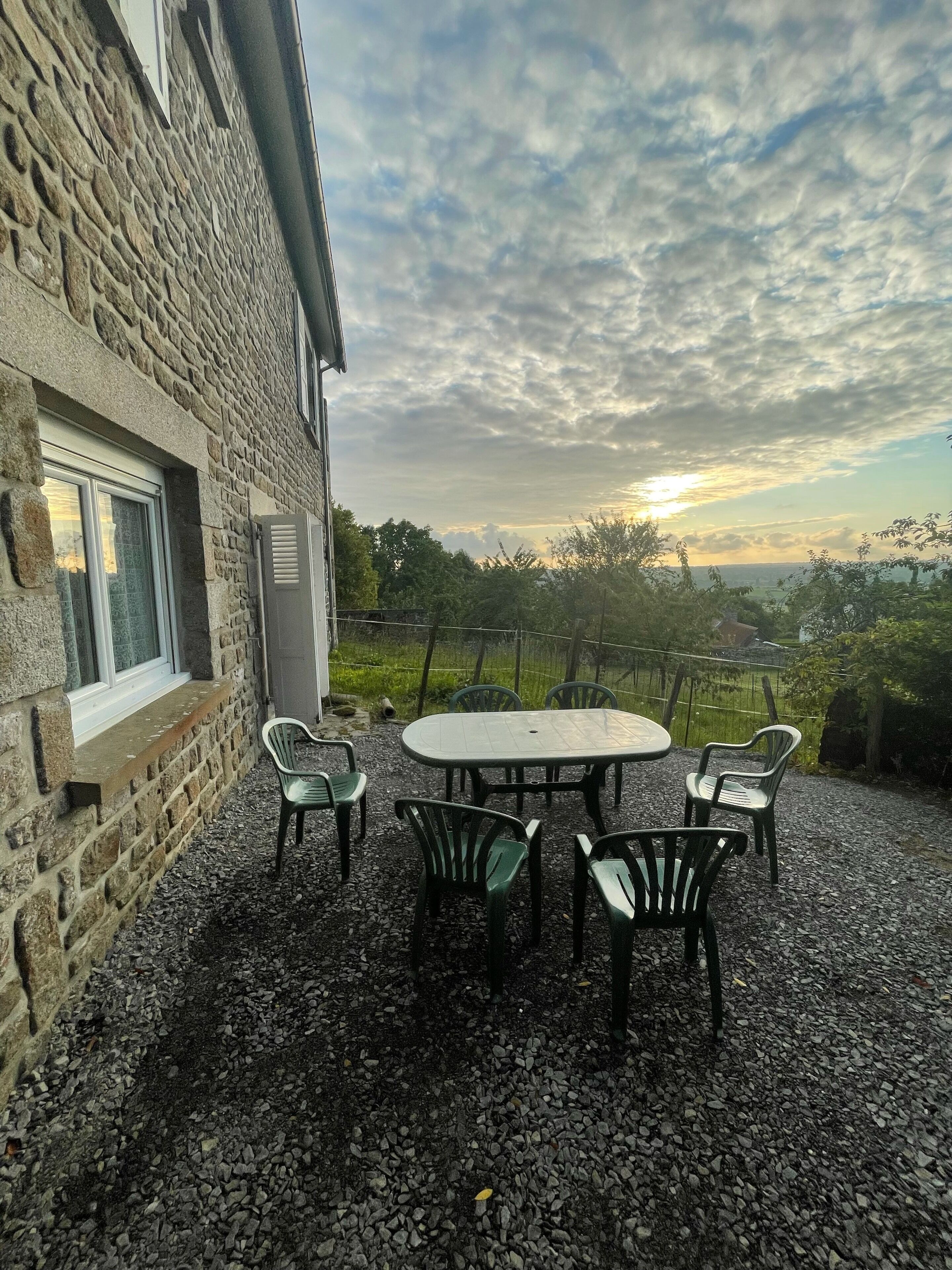 A stone building with a gravel patio, outdoor seating, and a view of the landscape.