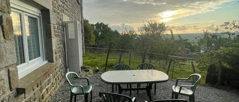 A stone building with a gravel patio, outdoor seating, and a view of the landscape.