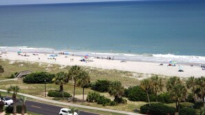 A beach with people, umbrellas, and palm trees. - Oceanfront Condo in Myrtle Beach  (Myrtle Beach)