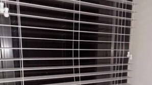 Una ventana con persianas horizontales y una pequeña placa con la palabra 'Teamwork' en un alféizar inferior.