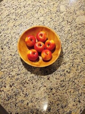 A bowl of fresh apples sits atop a countertop.