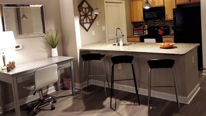 Una cocina moderna con una isla central, taburetes de bar, microondas y armarios de madera.