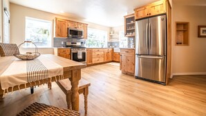 Una cocina amplia con armarios de madera, electrodomésticos de acero inoxidable y un comedor con mesa y sillas.