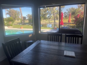 Un comedor con vistas a una piscina y una cancha de tenis.