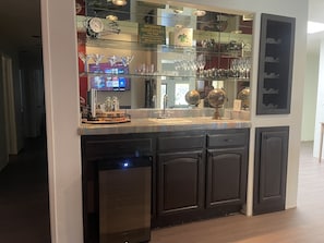 Una zona de bar con una vitrina de vidrio que contiene copas y botellas, un reloj y un cartel anunciando música e danza irlandesas.