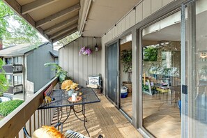 Une terrasse extérieure couverte, avec une table et des chaises, un panneau d’accueil et des plantes en pot.