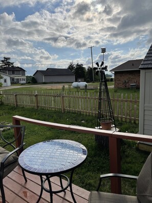 Une terrasse avec une table ronde et des chaises, une clôture en bois et, en arrière-plan, une vue sur des maisons et un silo.