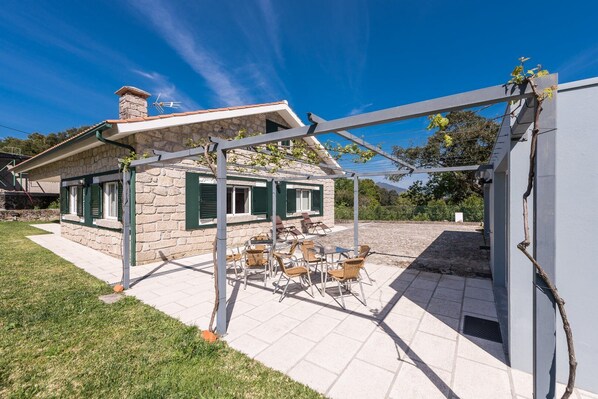 Una casa in pietra con patio, arredi esterni e una pergola.
