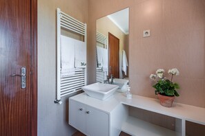 Un bagno moderno con un mobile vanitario bianco, uno specchio grande e una pianta in vaso.