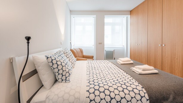Ein modernes Schlafzimmer mit einem Bett, einem Sessel, einem Kleiderschrank und einer Heizung.