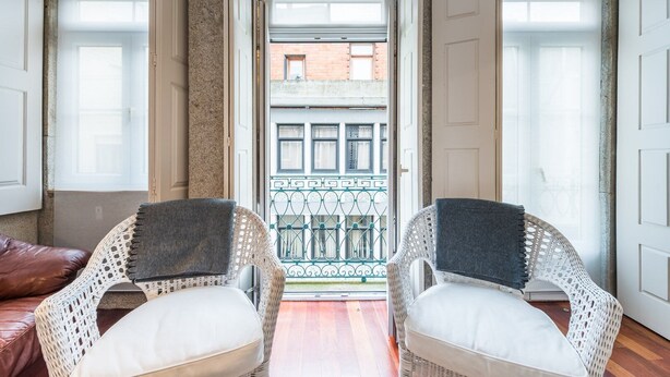Een balkon met rieten stoelen en uitzicht op een gebouw.