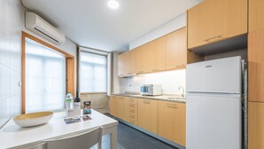 Een compacte keuken met houten kastjes, een witte koelkast, een magnetron en een spoelbak.