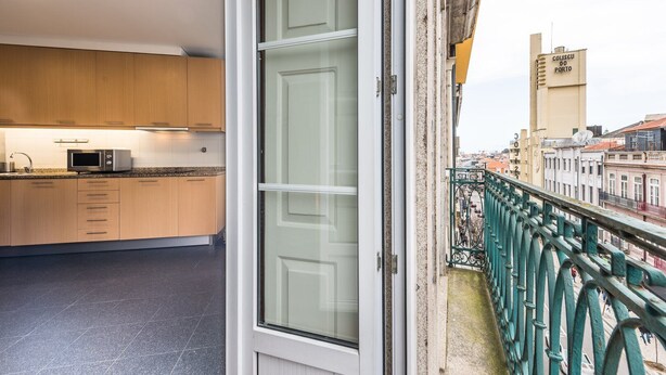 A modern kitchen with wooden cabinets, a microwave, and a window overlooking a cityscape.