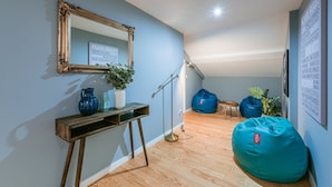 A modern living room with a wooden floor, a large mirror, a console table with vases, a floor lamp, and blue bean bags. - GuestReady - Miragaia Rooftop (Porto)