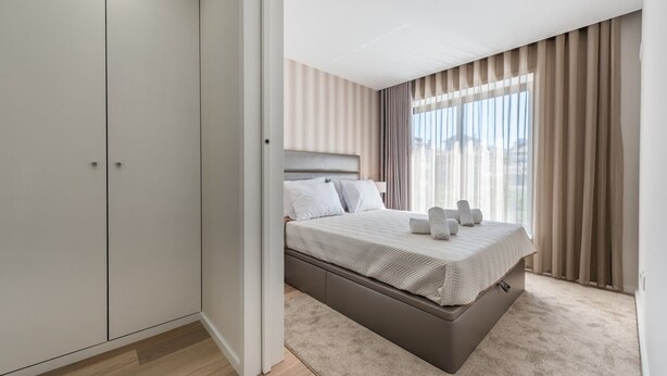 A modern bedroom with a bed, a wardrobe, and a large window with curtains. - GuestReady - Mushroom (Porto)