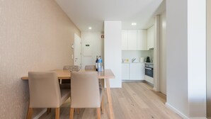 A modern kitchen with white cabinets, a built-in oven, and a coffee machine. - GuestReady - Mushroom (Porto)