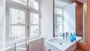 A modern bathroom with a large window, a white sink, and a mirror.