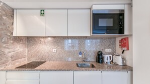 A compact kitchen with a granite countertop, a built-in microwave, a coffee maker, and a toaster.
