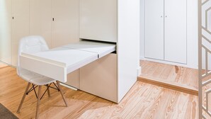 A compact room with a foldable desk, a chair, and a wardrobe.