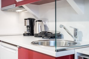Et moderne køkken med vask i rustfrit stål, kaffemaskine og brødrister.