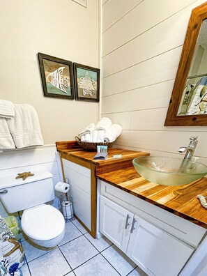 A bathroom with a glass sink, wooden countertop, and a framed fish artwork on the wall. - Beach Front Studio Direct Gulf View King and bunks (Panama City Beach)