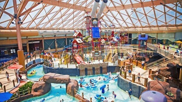 An indoor water park with multiple slides, water play areas, and a large central water feature.