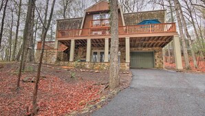 A two-story cabin with a stone foundation, wooden upper structure, and a balcony with a railing.