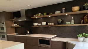 Een moderne keuken met een centraal eiland, een inbouwoven, magnetron en een roestvrijstalen afzuigkap.