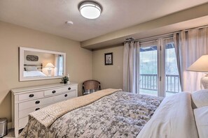 Une chambre à coucher avec un lit, une commode, un miroir et une fenêtre avec des rideaux.