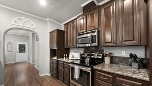 Una cocina moderna con armarios de madera oscura, electrodomésticos de acero inoxidable y encimera de granito.