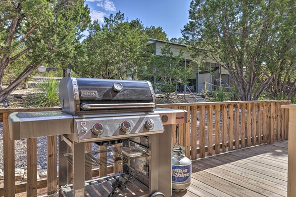 Un barbecue avec une bouteille de propane sur une terrasse en bois.